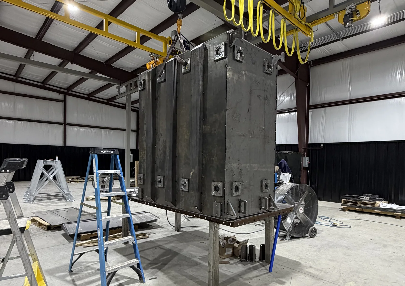 Corrugated-wall transformer tank under an overhead crane during fabrication at FabTek Industries in Hazlehurst, Mississippi
