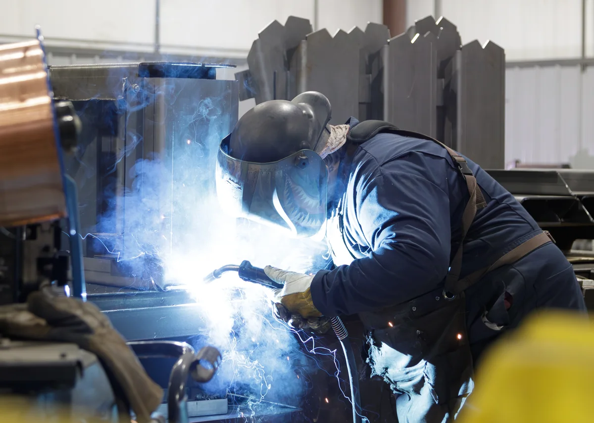 FabTek welder MIG-welding a fabricated steel assembly with sparks flying