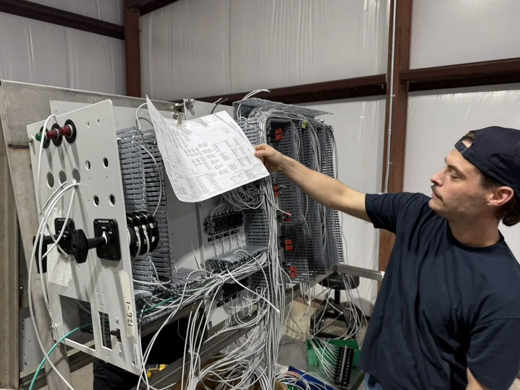 FabTek technician checking cabinet wire-out against a wiring schematic